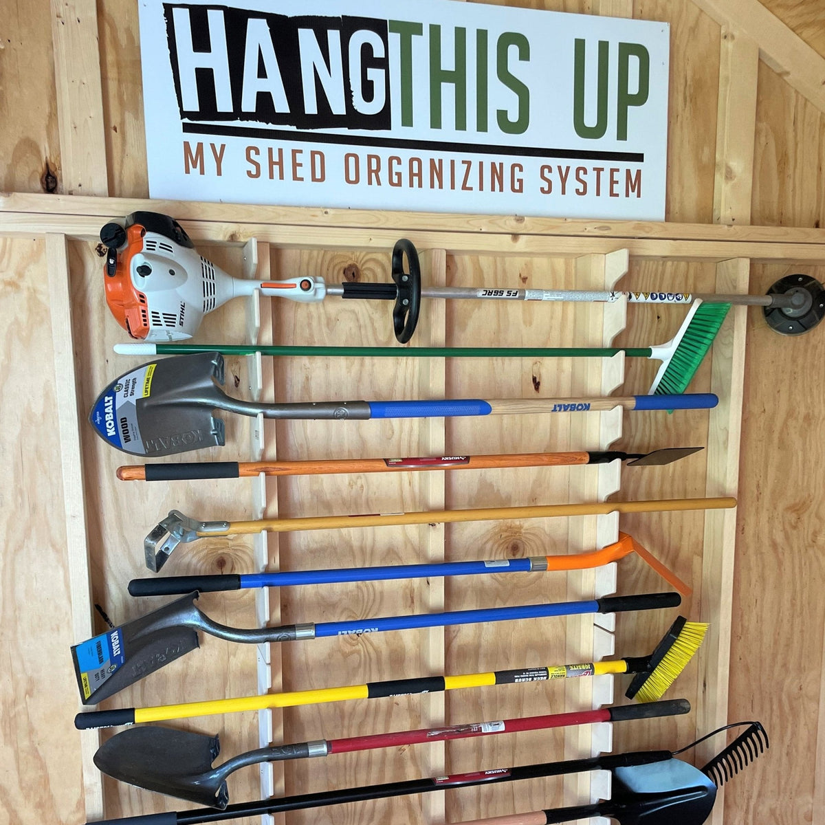 Stud-mounted garden tool organizer rack holding long-handled tools